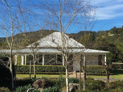 a white house with a tree in front of it at Lastover Cottage in Wattamolla