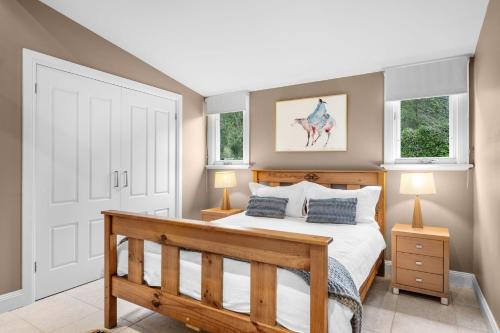 - une chambre avec un lit en bois et 2 fenêtres dans l'établissement Lastover Cottage, à Wattamolla