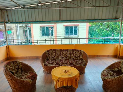 uma sala de estar com um sofá, cadeiras e uma mesa em Kanan Villa em Calcutá