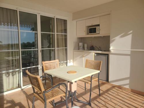 a kitchen with a table and chairs and a balcony at Studio vue mer sainte Luce in Sainte-Luce
