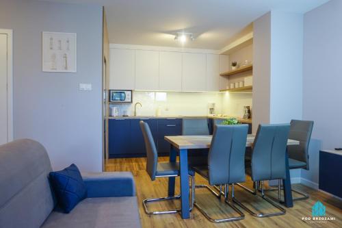 eine Küche mit einem Esstisch und blauen Stühlen in der Unterkunft Pod Brzozami Apartamenty Villa Solny in Ustronie Morskie