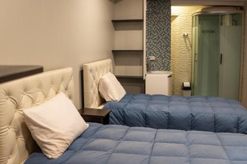 1 dormitorio con 2 camas y ducha en Hotel California Urubamba en Urubamba