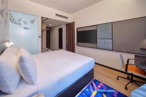 a bedroom with a large white bed and a tv at Aloft Singapore Novena in Singapore