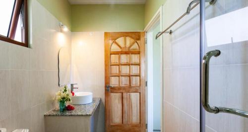 a bathroom with a sink and a shower with a door at Hyde-Tide Guesthouse in La Digue