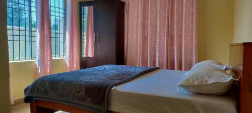 um quarto com uma cama com uma almofada e uma janela em Chesna Cottage em Madikeri