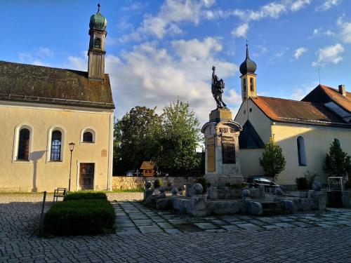 a church with a statue in front of a building at Hotel Alter Wirt in Weyarn
