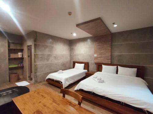 a bedroom with two beds and a table at Komol Residence Bangkok in Bangkok