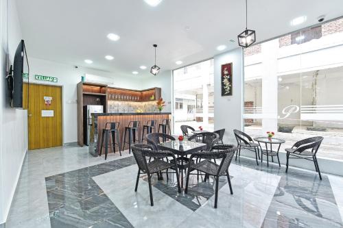 Capital O 90882 Padi Hotel في ألور سيتار: غرفة طعام مع طاولات وكراسي وبار