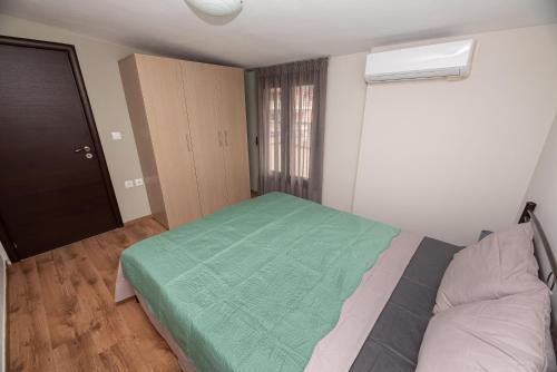um quarto com uma cama com um cobertor verde em Seacoast apartments 3 ! em Kamena Vourla