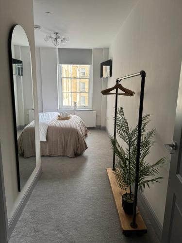 巴斯的住宿－Haus of Sulis, City Centre Apartment with Lift Access，一间卧室配有床、镜子和植物