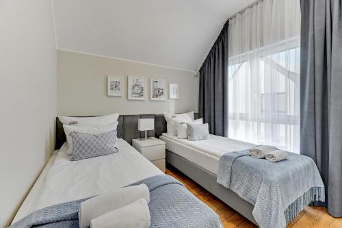 a bedroom with two beds and a window at Downtown Apartments Domy na Kuracyjnej - Jastrzębia Góra in Jastrzębia Góra