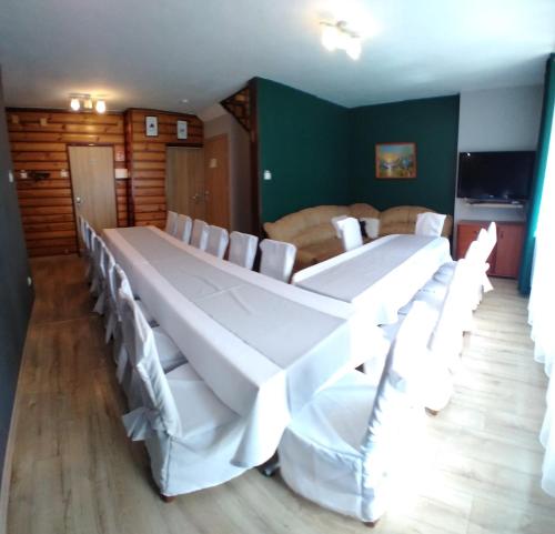 una habitación con una mesa larga y sillas blancas en Domki całoroczne u Eli, en Szczyrk