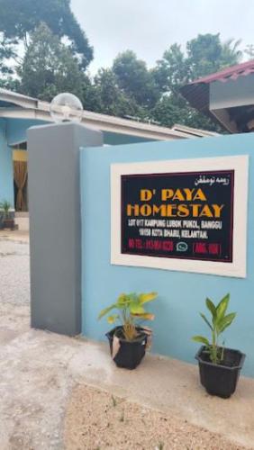 un cartel en una pared azul con dos macetas en D'PAYA HOMESTAY, en Bachok