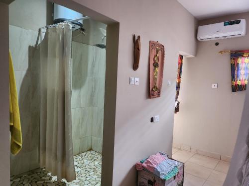La salle de bains est pourvue d'une douche avec rideau de douche. dans l'établissement POMBO KUNDA Room, à Sanyang
