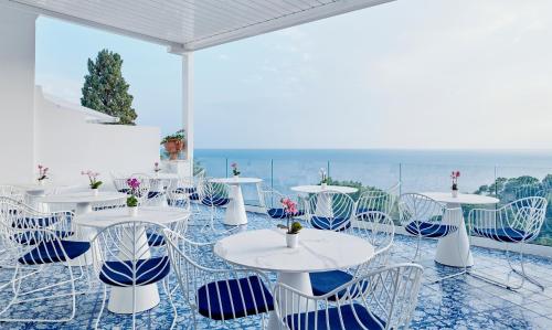 a room with tables and chairs with a view of the ocean at Hotel Scalinatella in Capri