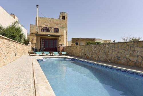 a swimming pool in front of a house at Ta' Karkar Villa Bed and Breakfast in Xagħra