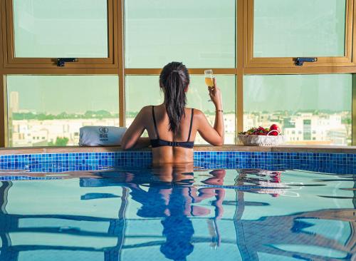 a woman in a bikini sitting in a swimming pool at AG Hotel in Abu Dhabi