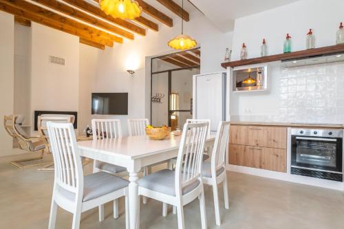 a kitchen and dining room with a white table and chairs at Can Serral in Algaida