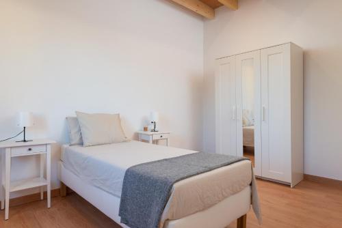 a white bedroom with a bed and a white cabinet at Can Serral in Algaida