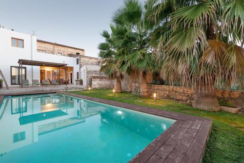 a swimming pool in front of a house with palm trees at Can Serral in Algaida