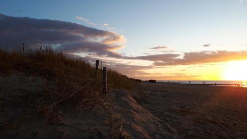 a sunset on a beach with a fence on it at Pension Haus Erika in Cuxhaven
