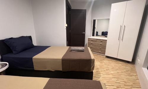 a small bedroom with two beds and a dresser at GreyStone Apartments in Nadi
