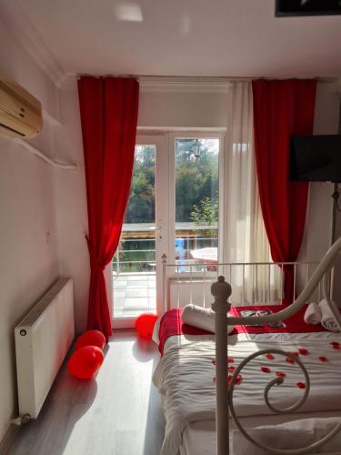 Schlafzimmer mit einem Bett mit roten Vorhängen und einem Fenster in der Unterkunft agva temmuz otel in Sile