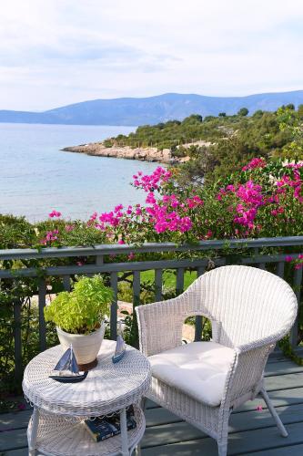 a wicker chair and a table on a deck with flowers at Villa Iris - Luxury traditional beachfront villa with swimming pool in Koilás
