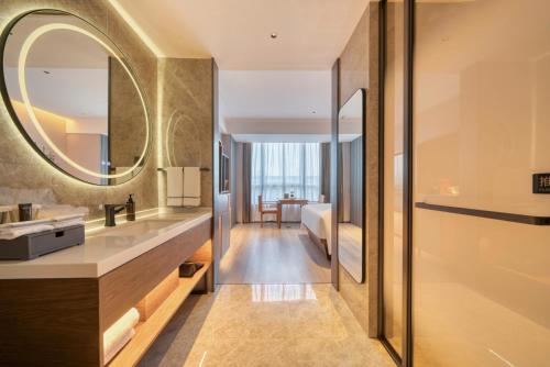 La salle de bains est pourvue d'un lavabo et d'un miroir. dans l'établissement UrCove Hangzhou North Grand Canal, à Hangzhou
