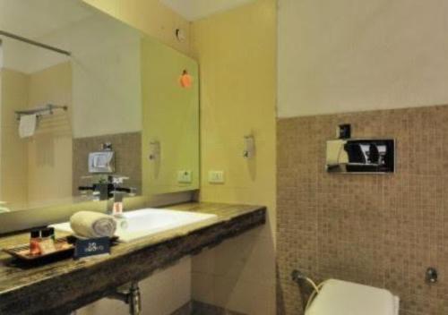 a bathroom with a sink and a mirror and a toilet at Hotel Landmark in Chandīgarh