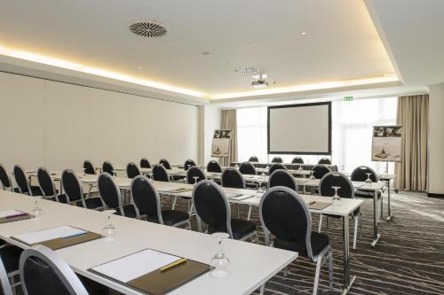 a conference room with tables and chairs and a screen at Mercure Düsseldorf Kaarst in Kaarst