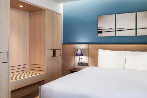 a bedroom with a white bed and a blue wall at Parnas Hotel Jeju in Seogwipo