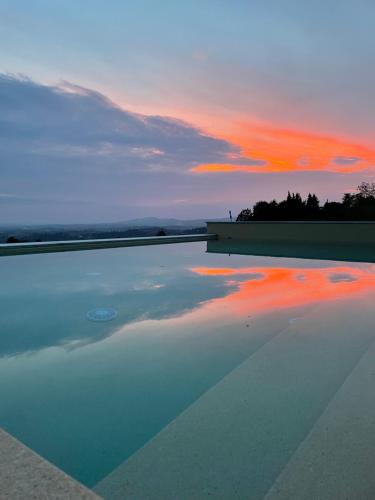 a pool of water with a sunset in the background at Alle tre Colline in Albugnano 