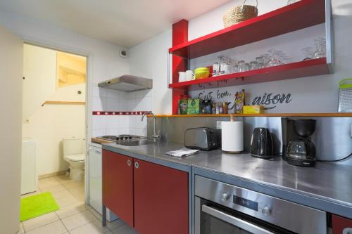 eine Küche mit roten Schränken und einer Arbeitsplatte in der Unterkunft Logement Coquelicot - 6 personnes in Hillion