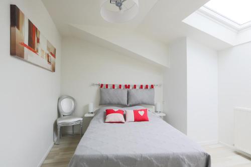 ein weißes Schlafzimmer mit einem Bett mit roten Kissen in der Unterkunft Logement Coquelicot - 6 personnes in Hillion