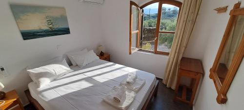 a bedroom with a large white bed with a window at Porto Heli Apartments in Palekastron