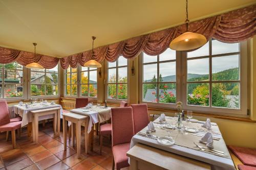 um restaurante com mesas, cadeiras e janelas em Hotel Pod Jasany em Spindleruv Mlyn