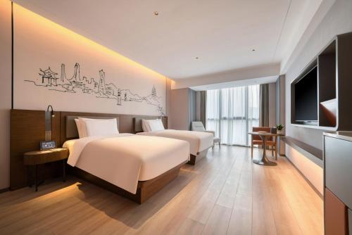 a hotel room with two beds and a flat screen tv at UrCove Hangzhou North Grand Canal in Hangzhou