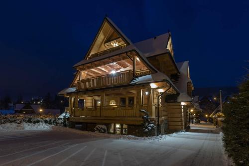 a log cabin in the snow at night at Aparthotel Bambi in Zakopane