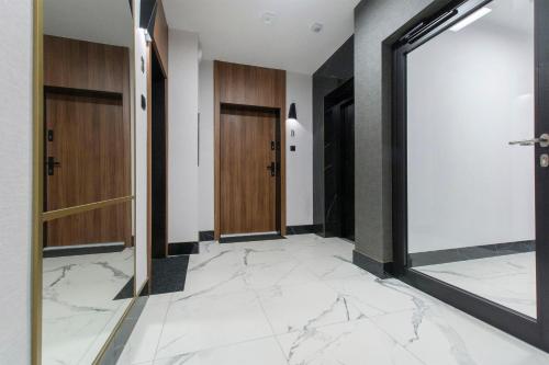korytarz z marmurową podłogą i drewnianymi drzwiami w obiekcie Devalia Rentyear Apartments w Gdańsku