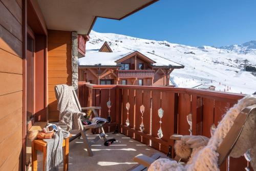a balcony with rocking chairs and a snow covered mountain at Résidence Pierre & Vacances Premium Les Alpages de Reberty in Les Menuires