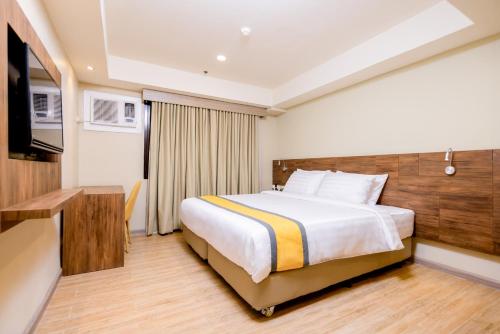 a hotel room with a bed and a television at SureStay Plus by Best Western Cebu City in Cebu City