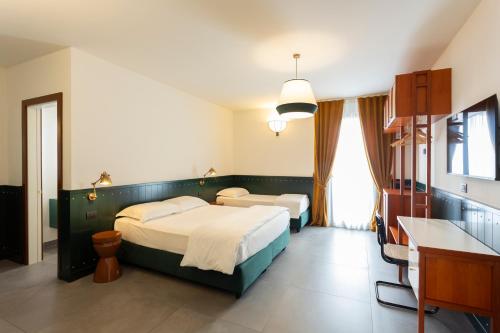 una camera d'albergo con 2 letti e una scrivania di Hotel Ghalà a Galatone