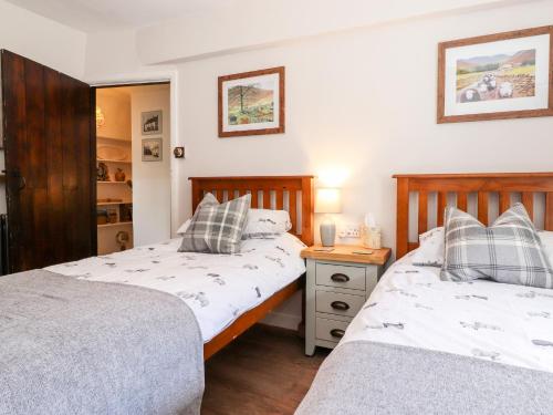 a bedroom with two beds and a night stand at Orchard Cottage in Windermere