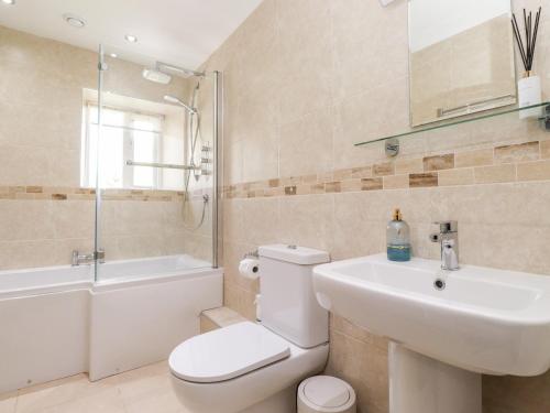 Un baño con inodoro, lavabo y ducha. en Orchard Cottage, en Windermere