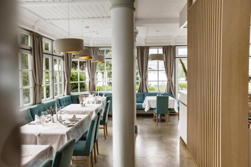a restaurant with white tables and green chairs at Hotel Brandauers Villen Superior in Strobl