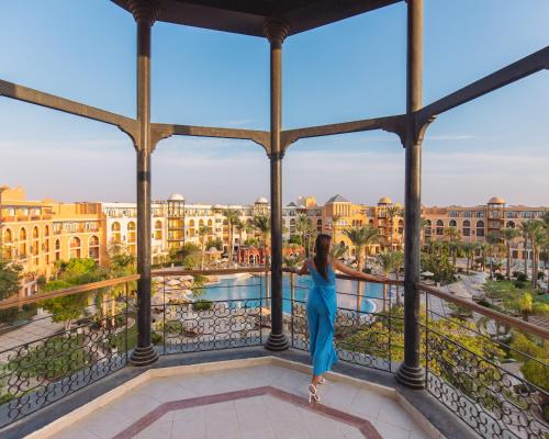 uma mulher de vestido azul em pé numa varanda com vista para a cidade em The Grand Resort em Hurghada