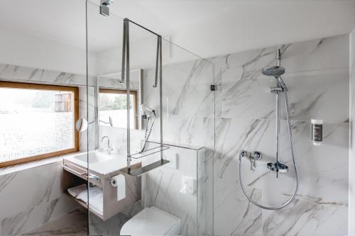 a white bathroom with a shower and a sink at Seehotel Brandauer's Villen in Strobl