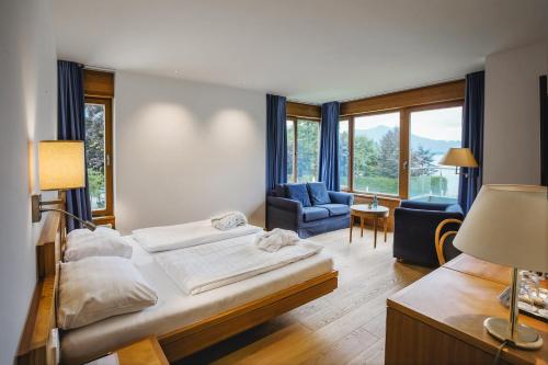 um quarto com uma cama, um sofá e uma cadeira em Hotel Brandauers Villen Superior em Strobl