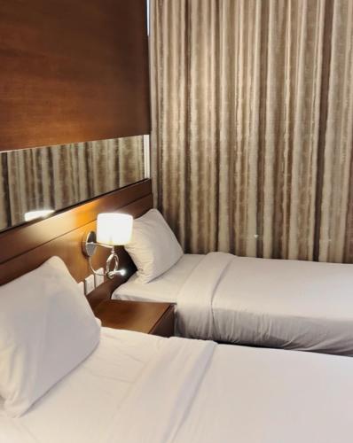 a hotel room with two beds and a lamp at The Seventh Star Hotel Suites in Amman